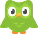 Duo the green owl mascot with large white eyes and an orange beak staring directly forward.