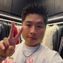 A man making a peace sign gesture with his hand while smiling.