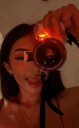 Woman taking a selfie with a camera while cycling through different colored flash filters.