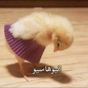 A fluffy yellow chick wearing a purple skirt looking down bashfully.
