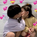 A young boy and girl kissing with pink heart overlays.