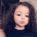 A toddler with curly hair blows a kiss at the camera.