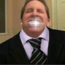 Man in a suit and tie displaying an intensely sparkling, bright white smile.