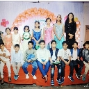 A group of children standing and sitting together in formal clothing for a celebration photo.