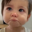 Toddler with a pouting expression and glassy eyes looking like they are about to cry.