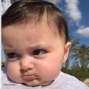 Baby with a skeptical and annoyed facial expression looking off to the side.