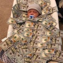 A baby wearing a hat and pacifier lies in a crib buried under a large pile of hundred-dollar bills.