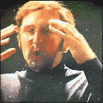 A man in a black turtleneck experiences his head exploding in a dramatic, cinematic sequence.
