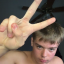 A young person making a peace sign gesture with their hand while looking at the camera.