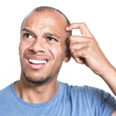 A man scratching his head with a confused and puzzled expression.