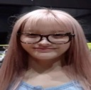 A girl with pink hair and glasses staring with a blank, deadpan expression.
