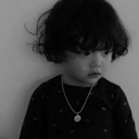 Toddler with messy hair looking sideways with a serious and unimpressed expression.