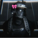 A tactical soldier wearing a dark helmet with a small pink bow attached to the side.