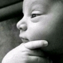 Baby resting their chin on their hand with a thoughtful and skeptical expression.