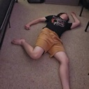 Person lying flat on their back on a carpeted floor in a pose of total exhaustion.