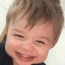 Toddler with a wide, squinting, mischievous grin.