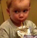 A young child looking sideways with a suspicious expression while holding a juice pouch.