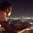 Giannis Antetokounmpo looking out over a city at night with a contemplative expression.