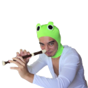 Person wearing a green frog hat playing a recorder with a mischievous expression.