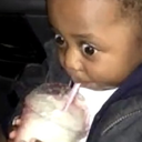 Young boy with wide, shocked eyes drinking from a plastic cup with a straw.