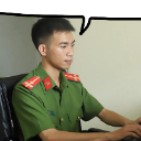 Vietnamese police officer in uniform looking intently at a computer screen with a speech bubble above his head.