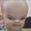 Baby face with a heavily distorted, wide-angle lens effect creating a large head and intense expression.