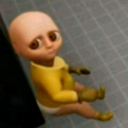 A bald baby with oversized, soulful eyes sitting and staring blankly.