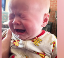 Baby crying with eyes squeezed shut and mouth wide open in distress.