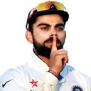 Virat Kohli wearing a cricket cap and white jersey holds a finger to his lips in a shushing gesture.