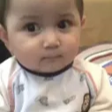 A baby with a deadpan, unamused expression staring directly into the camera.