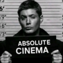 Dean Winchester holding a mugshot sign that says Absolute Cinema.