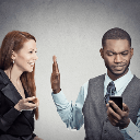 Man holding up his hand to stop a woman from speaking while looking at his smartphone.