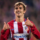 Antoine Griezmann smiling and making a telephone hand gesture with both hands.