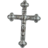 A detailed silver cross with ornate edges against a black background.