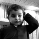 A young child looking confused while scratching their head in a black and white photo.