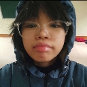 Person wearing a blue hoodie and glasses looking directly at the camera with a neutral, unimpressed expression.