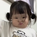 A toddler with pigtails making a skeptical, unimpressed face with pursed lips.
