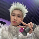 A person with spiky bleached hair making a peace sign gesture.