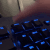 A finger pressing the print screen key on a backlit mechanical keyboard.