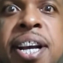 A man with wide, intense eyes and bared teeth looking directly at the camera in a shocked expression.