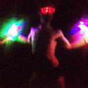A person dancing in the dark while holding glowing neon sticks.