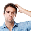 A man scratching his head with a confused and thoughtful expression.