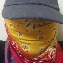 Person wearing a yellow patterned bandana mask and a gray baseball cap covering their eyes.