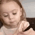 A toddler with a serious expression holding a pen and looking down in concentration.