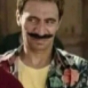 A man with a thick mustache giving a sly, sideways smirk.