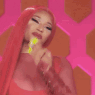 Nicki Minaj blows a kiss with a confident smile and bright yellow nails.