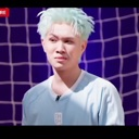 A man with light blue hair looking at the camera with a skeptical and judgmental expression.