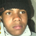 Young person wearing a black beanie looking directly at the camera with a serious, unimpressed expression.