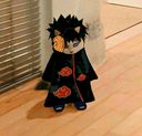 A small cat wearing an Akatsuki cloak and an orange Tobi mask standing on a wooden floor.