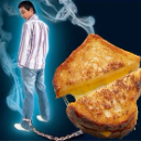 A man in a striped shirt is chained by his ankle to a large, toasted grilled cheese sandwich against a dark blue, smoky back…